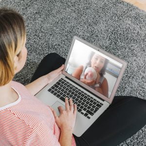 Γονέας συμμετέχει σε διαδικτυακό σεμινάριο με το παιδί του μέσω laptop.